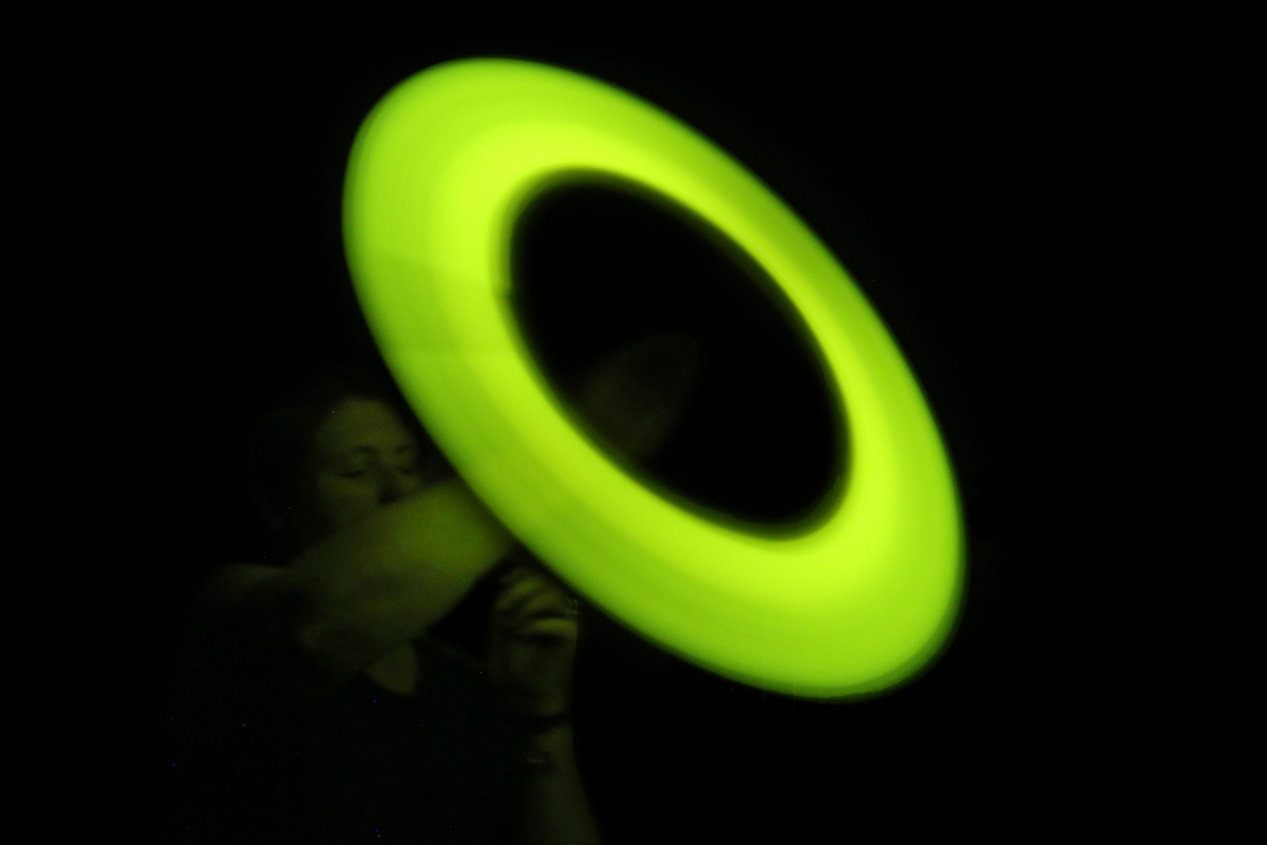 A glowing light stick being swung in a circle on a string creating the illusion of a large, glowing circle.