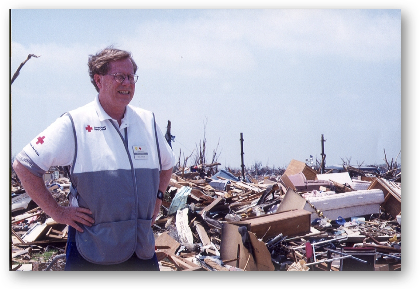 Image of Dr. Richard Heaps, American Red Cross response volunteer, standing in front of tornado debris pile.