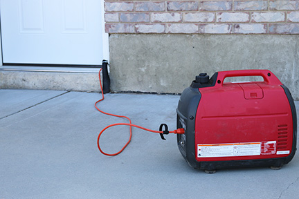 Generator running outside with extension cord running to a door and inside 