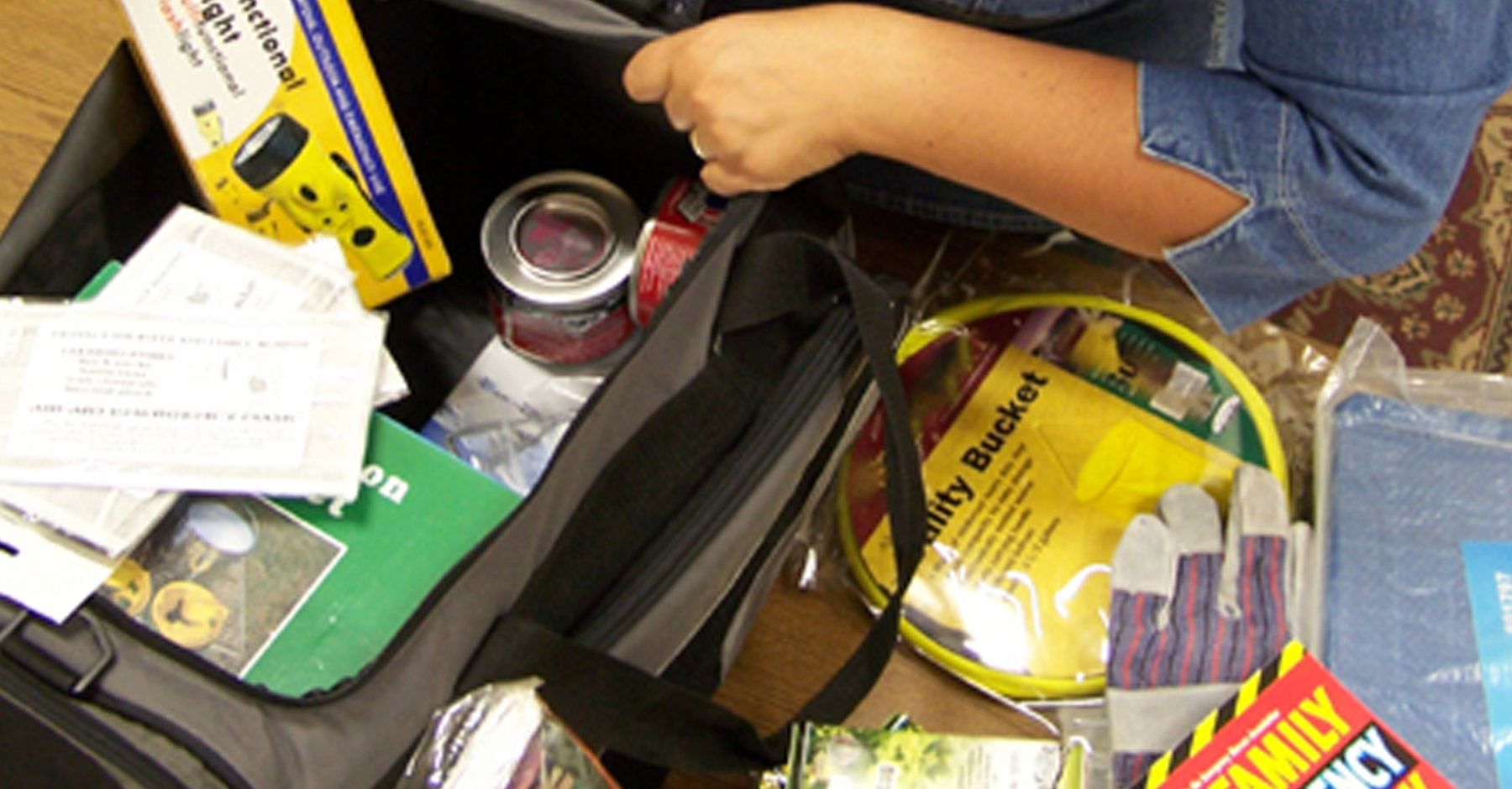 Woman packing emergency items into a duffle bag.