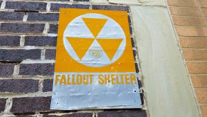 Image of a nuclear Fallout Shelter sign attached to a brick building. 